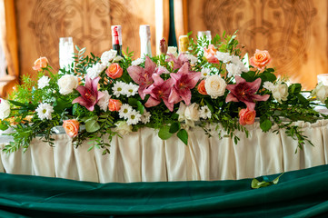 Flowers decorate a table with bottles in the background