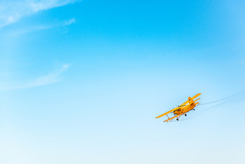 Fototapeta na wymiar Yellow retro biplane flying in the sky