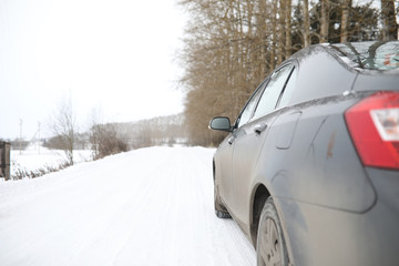 Car on a snowy winter road in fields.
