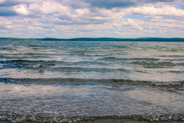 Small waves on the lake under the heavy cloudy sky. Nature landscape.