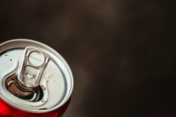 lighted tin open can with a soft drink in his hand on a dark background; there is a lot of copy...