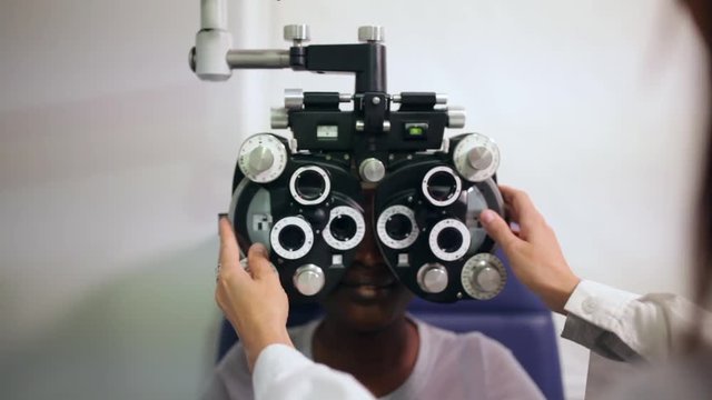 front view of an afro woman in an optometry cabinet correcting her eyesight