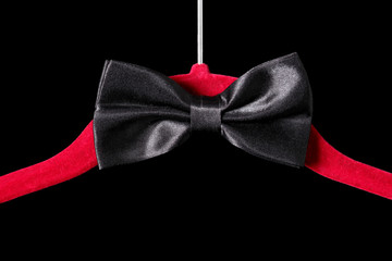 tie bow on a red velvet hanger isolated on black background with copy space for your text