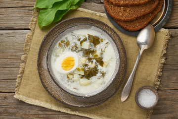 sorrel soup with cream and eggs, wooden background, top view