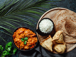 Indian cuisine dishes: tikka masala, rice, samosa, chapati,. Indian food on dark background with...