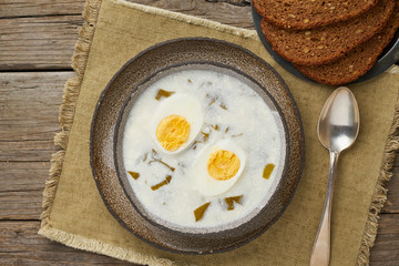 sorrel soup with cream and eggs, wooden background, top view