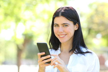 Happy adult woman holding phone looking at camera