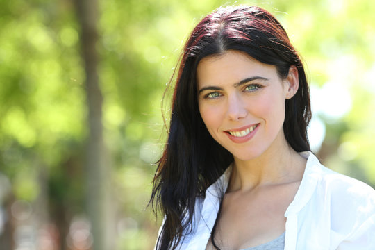 Beautiful brunnete woman looks at camera in a park