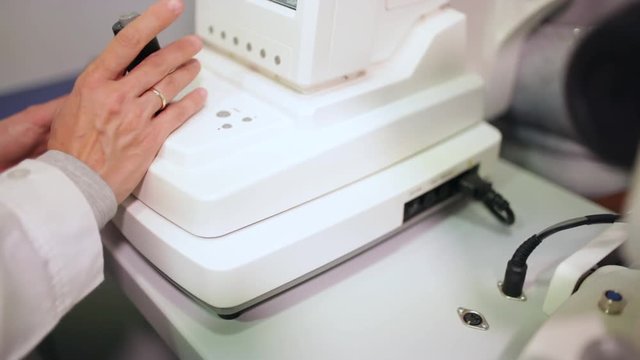 Ophthalmologist's hand using an ophthalmometer in his optometry cabinet