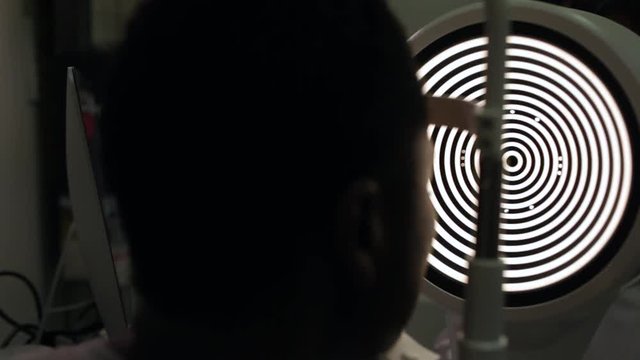ide view of an afro woman in an optometry cabinet correcting her eyesight with a ophthalmometer