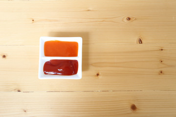 Ketchup and chilli sauce on horizontal compartment bowl on wood table righ copy space