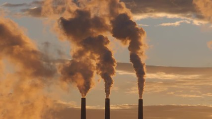 Telephoto shot of three coal-fired power plant towers emitting vapor during surise