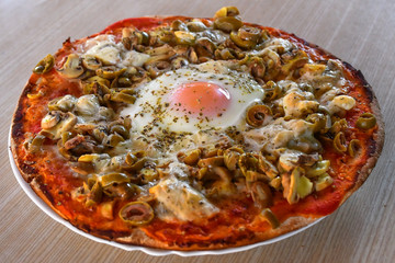 Pizza with cheese, mushrooms, olives and egg in the middle