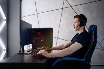 Professional gamer in his expensive studio young man having live stream playing online video game. Cyber sportsman is streaming popular pc computer game for his followers     