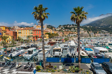 View of palm tree and harbor with boats in Menton on French Riviera. Provence-Alpes-Cote d'Azur,...