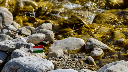 flag of Hungary among stones and glittering river water