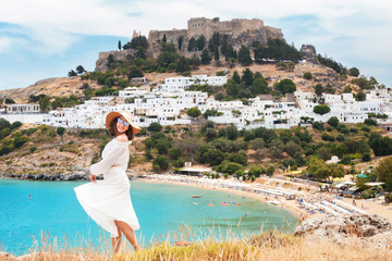 Happy asian woman travels in Greece. Having fun at the stunning view on sea resort and old town of Lindos on the mountain