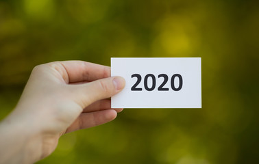 White paper card with black text in woman hand on green