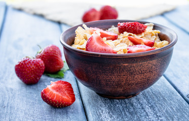 Fresh homemade muesli, muesli with strawberries in a plate on a blue background