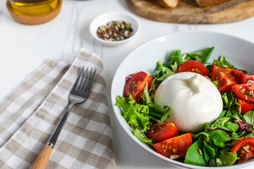 Fresh salad with italian burrata cheese, juicy tomatoes, balsamic vinegar and olive oil