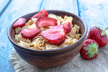 Fresh homemade muesli, muesli with strawberries in a plate on a blue background