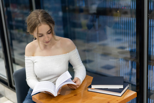 a girl in a bookstore is reading a book, preparing for a new school year. Theme education, personal development. Copy space