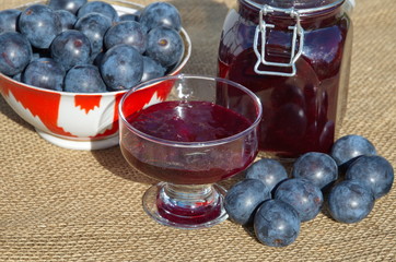 Homemade plum jam in a glass jar and fresh plums close-up