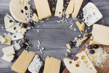 Circular frame made with different type of cheese and olives on wooden table