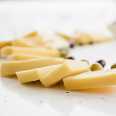 Fresh delicious cheese slices with olives on white desk