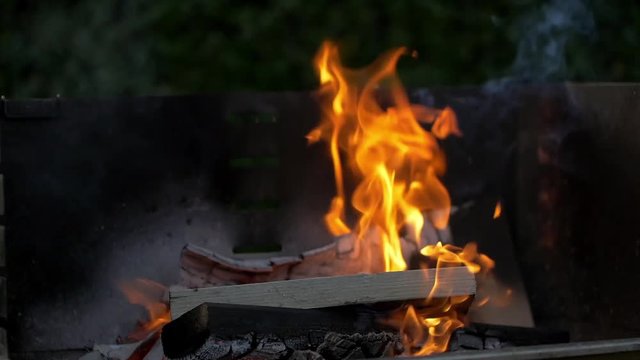 Burning Wood With Flames And Fire In Slow Motion, a stack of wood on a grill burns down in slow motion. filmed in 200fps.