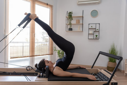 Young woman exercising on pilates reformer bed