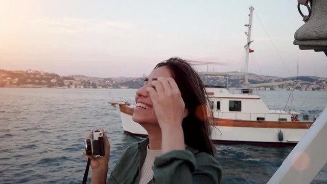 Beautiful young girl takes a picture while having a boat tour with view of bosphorus and landmarks in istanbul,Turkey.
