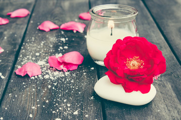 Natural cosmetic soap with red roses and a hot candle on a dark wooden background.
