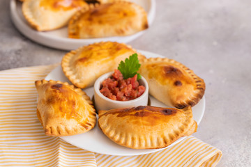 Homemade Spanish Empanadillas, small filling tuna pies served with tomato souse. Typical dish in Latin American and Spain cuisine.