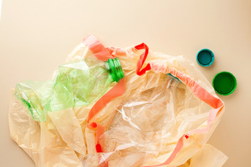 Used empty plastic water bottles crushed and crumpled in garbage bag for sorting (segregating) and recycling on coral pink background top view.Plastic free.Recycle household waste management concept