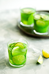 Homemade trendy iced matcha green tea or lemonade with cucumber and lime in a glass on light gray background.Healthy cold vegan beverage for hot summer day.Super food drink.Vertical orientation