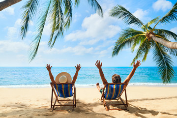 Happy couple with arms up relax on the beach enjoy beautiful sea on the tropical island