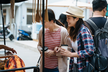 group of young people buying street food from pedicab stand vendor at holiday outdoor market. two...