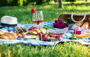 Summer picnic in the park on the grass. Wine, fruit and croissants