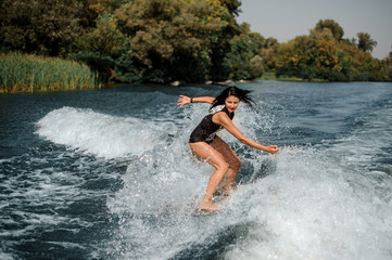 Fototapeta premium Brunette surfgirl on a surfboard near seashore