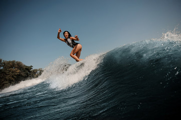 Brunette woman surfing on surfboard in sea - obrazy, fototapety, plakaty