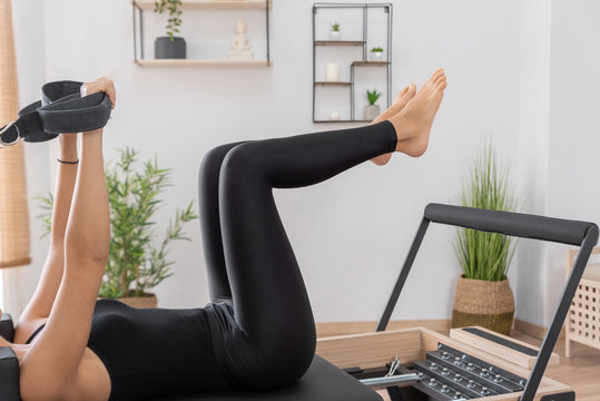 Young woman exercising on pilates reformer bed