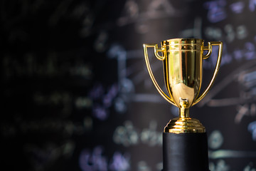 Achievement success in education awards concept: Golden trophy cup winner on blur formula equation...