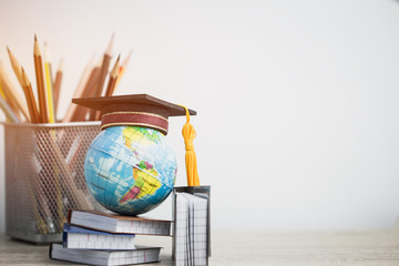 Concept of global business study abroad education. Graduation hat on models globe, books with...