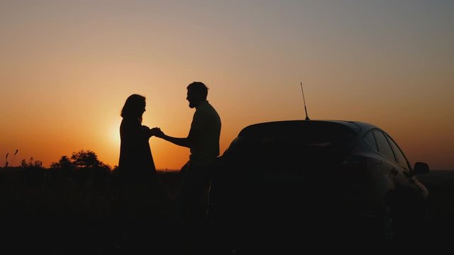 Romantic couple at sunset near the car