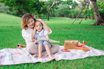Asian grandparents and granddaughter are lying on the grass field outdoor