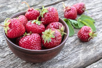 Fresh strawberries in a bowl on a wooden table.