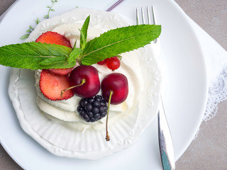 Meringues Pavlova cakes with fresh berry on concrete background, top view