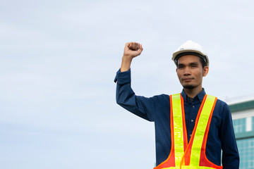 Engineering holding hand success and wears a white safety hat while working. Background building structure
