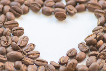 Ein Haufen geröstete Kaffeebohnen mit einem Loch in Herzform auf weißem Hintergrund lädt zum Kaffeegenuss ein